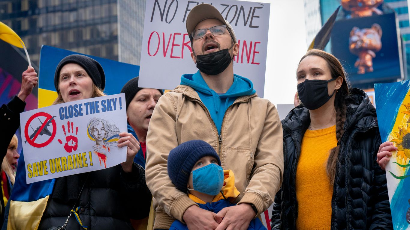 a group of people holding signs and wearing masks