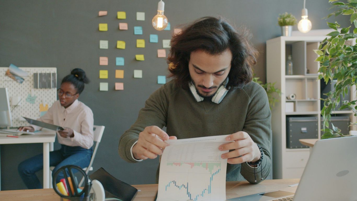 Man reviewing charts at a modern office desk.