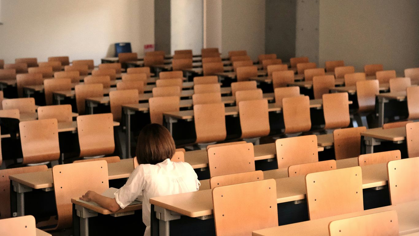 a young girl sitting in a classroom with a book