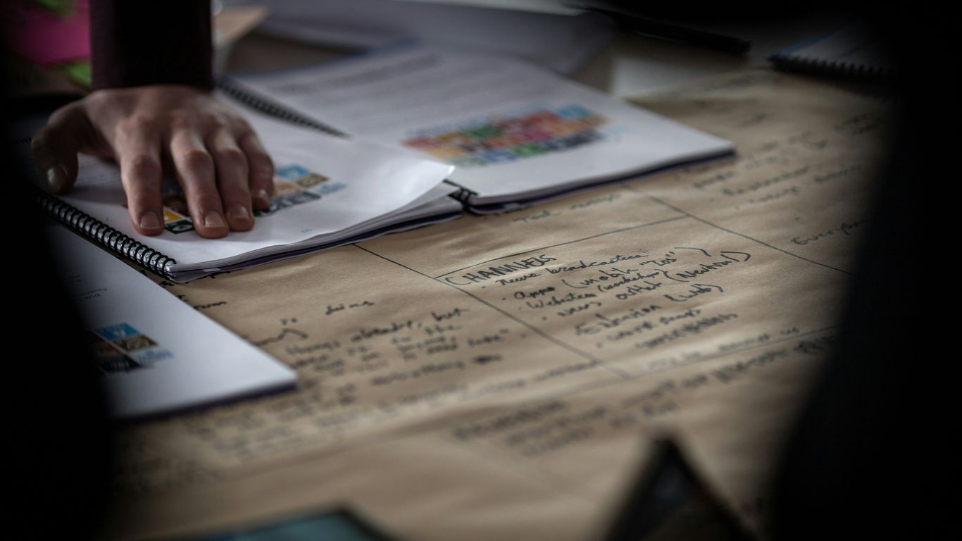 a person writing on a notebook with a pen