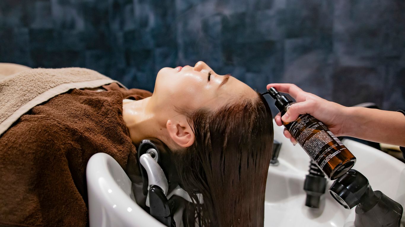 a woman getting her hair washed in a sink