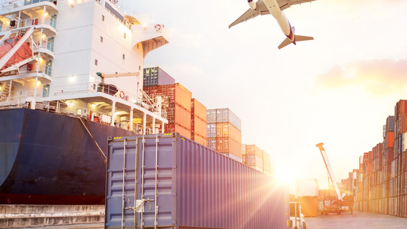 Cargo ship, truck, airplane, and shipping containers at a port.