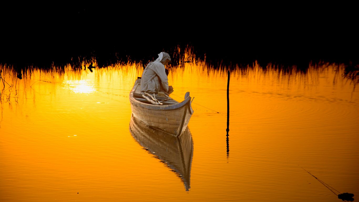 Man in a boat on golden water at sunset