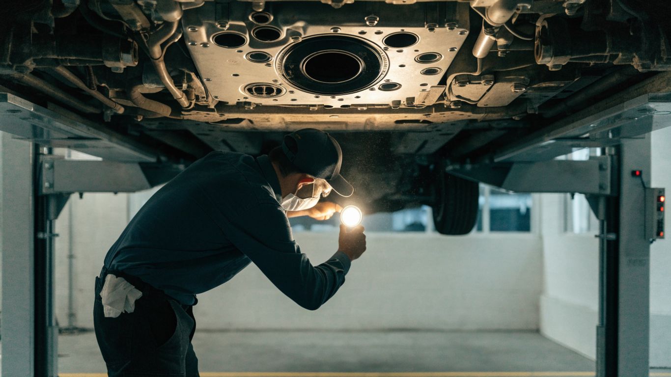 Technician inspecting a vehicle undercarriage for leaks