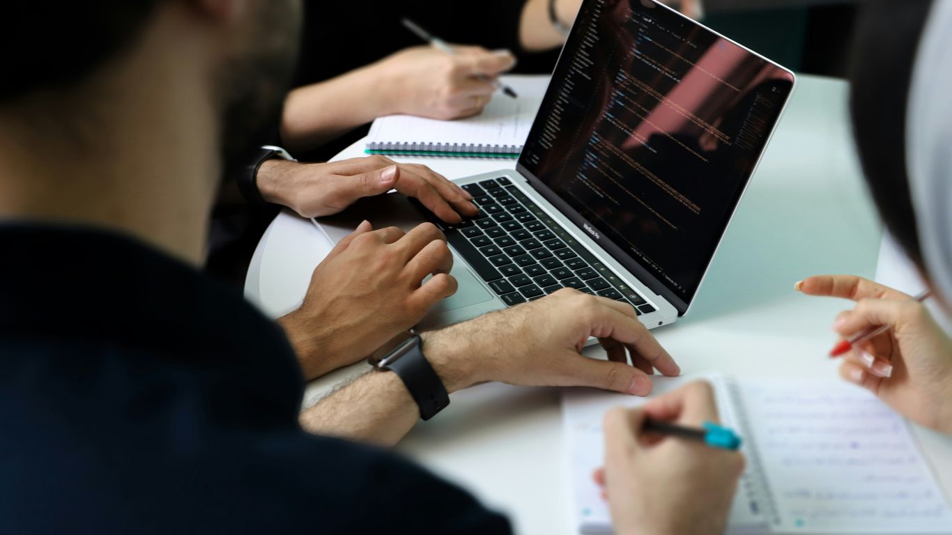 a group of people sitting around a laptop computer