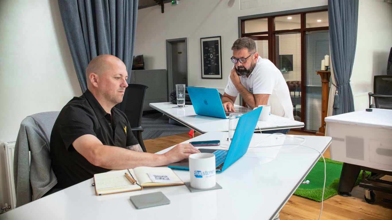 Two men working on laptops in a modern office.