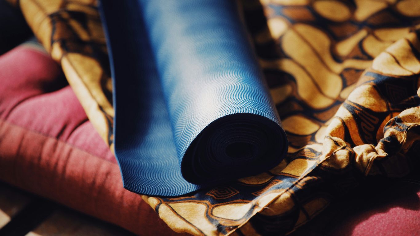 Rolled yoga mat beside travel bag
