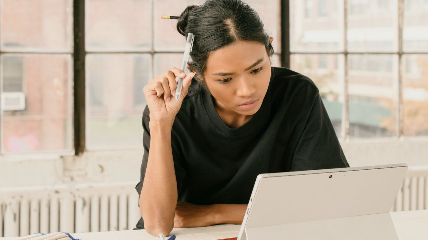 a woman sitting at a table using a laptop computer