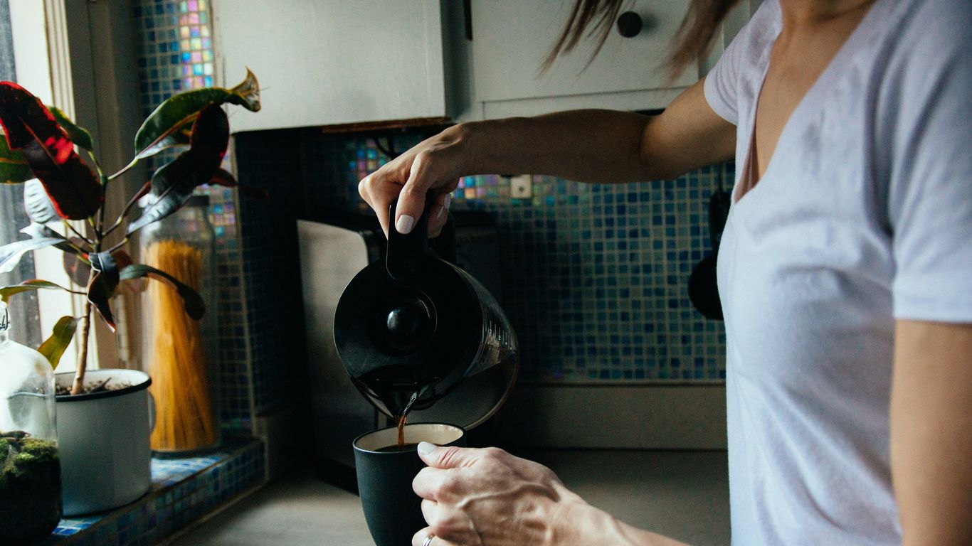 woman in white t-shirt holding black ceramic mug