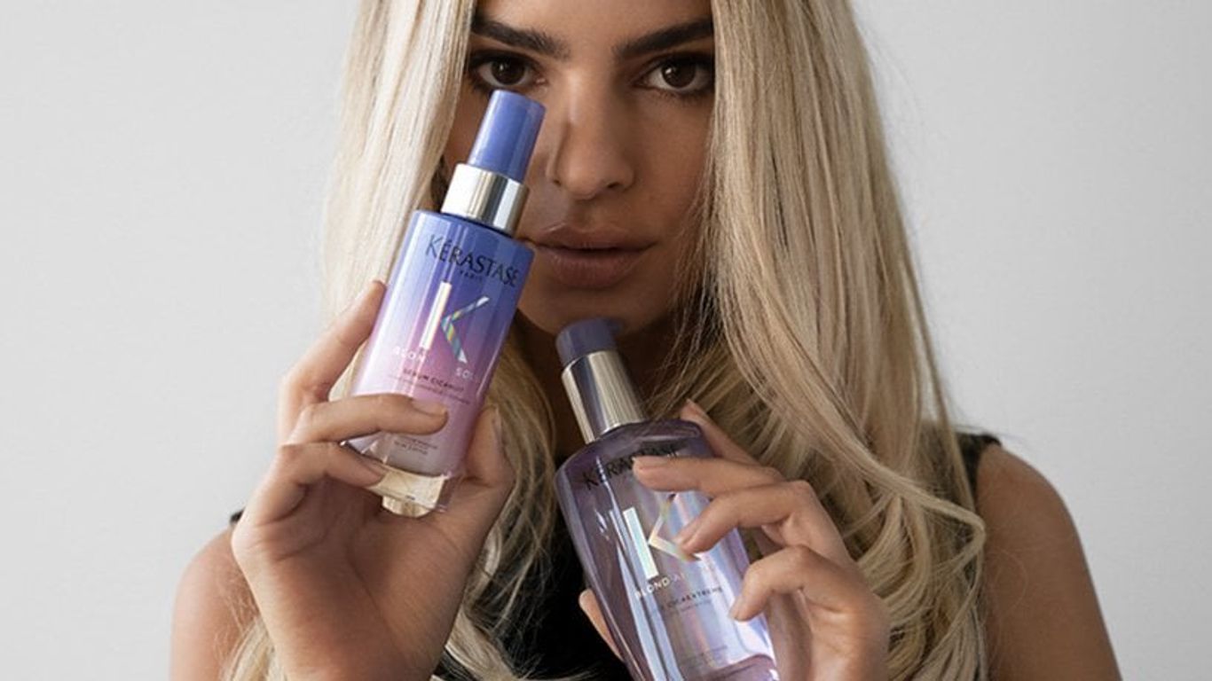 A person holding two bottles of Kérastase haircare products.