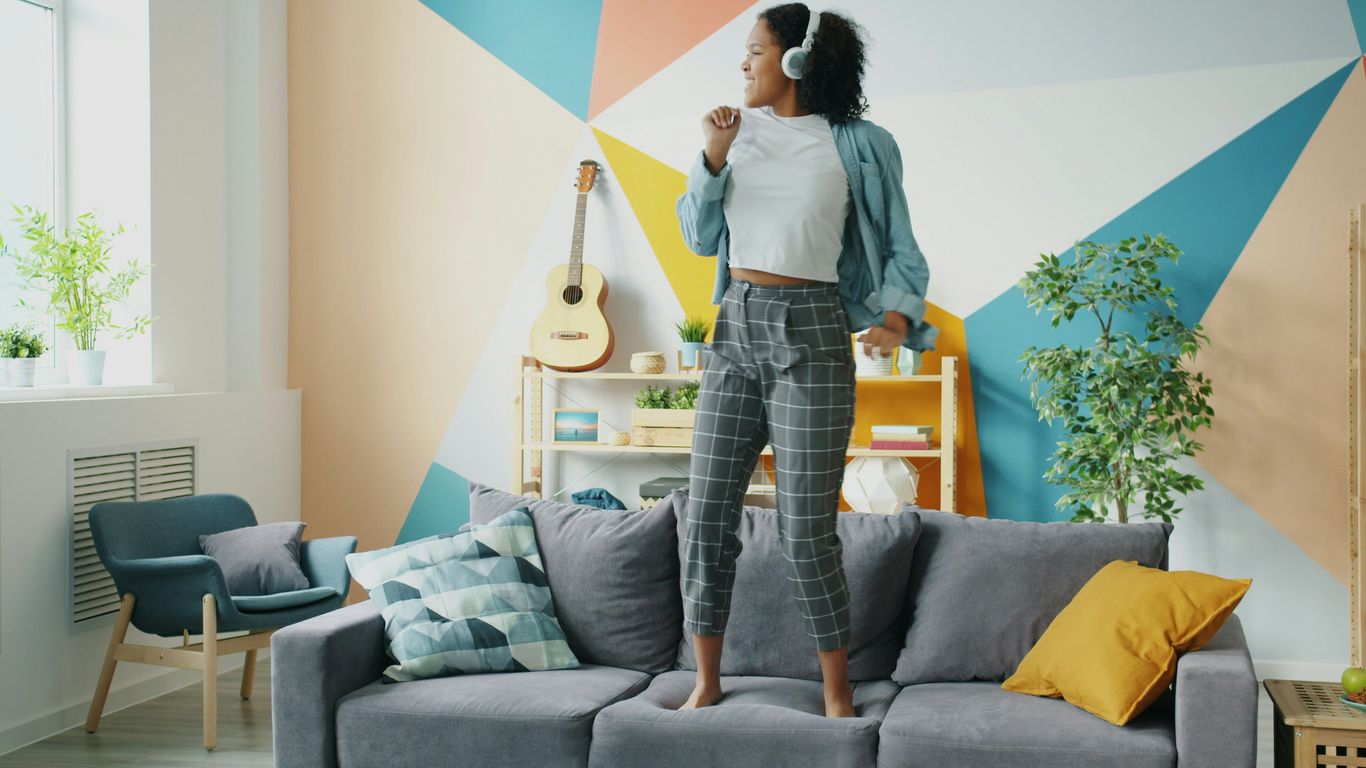 Woman dancing on couch listening to music