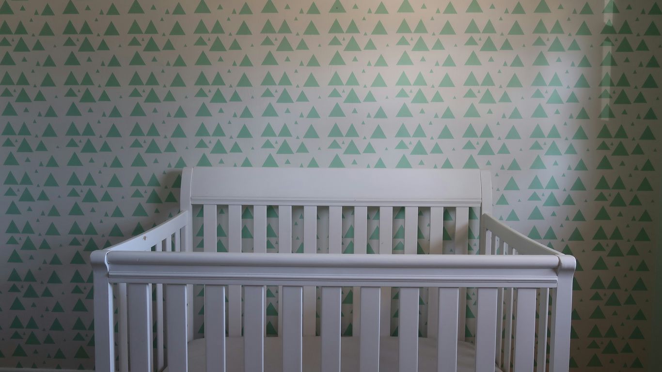 white wooden crib with white and blue polka dot wall