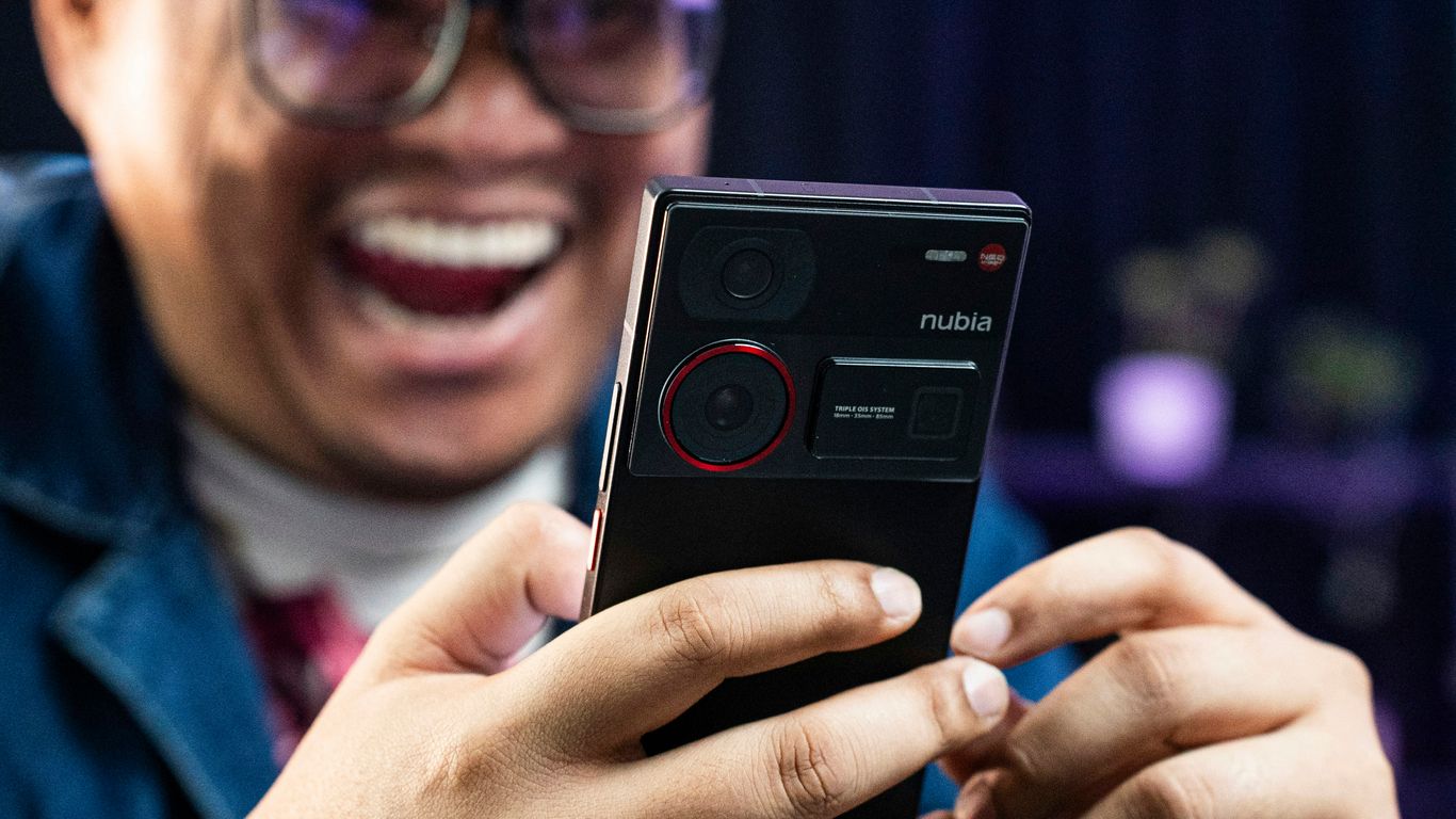 A man laughing while holding a cell phone