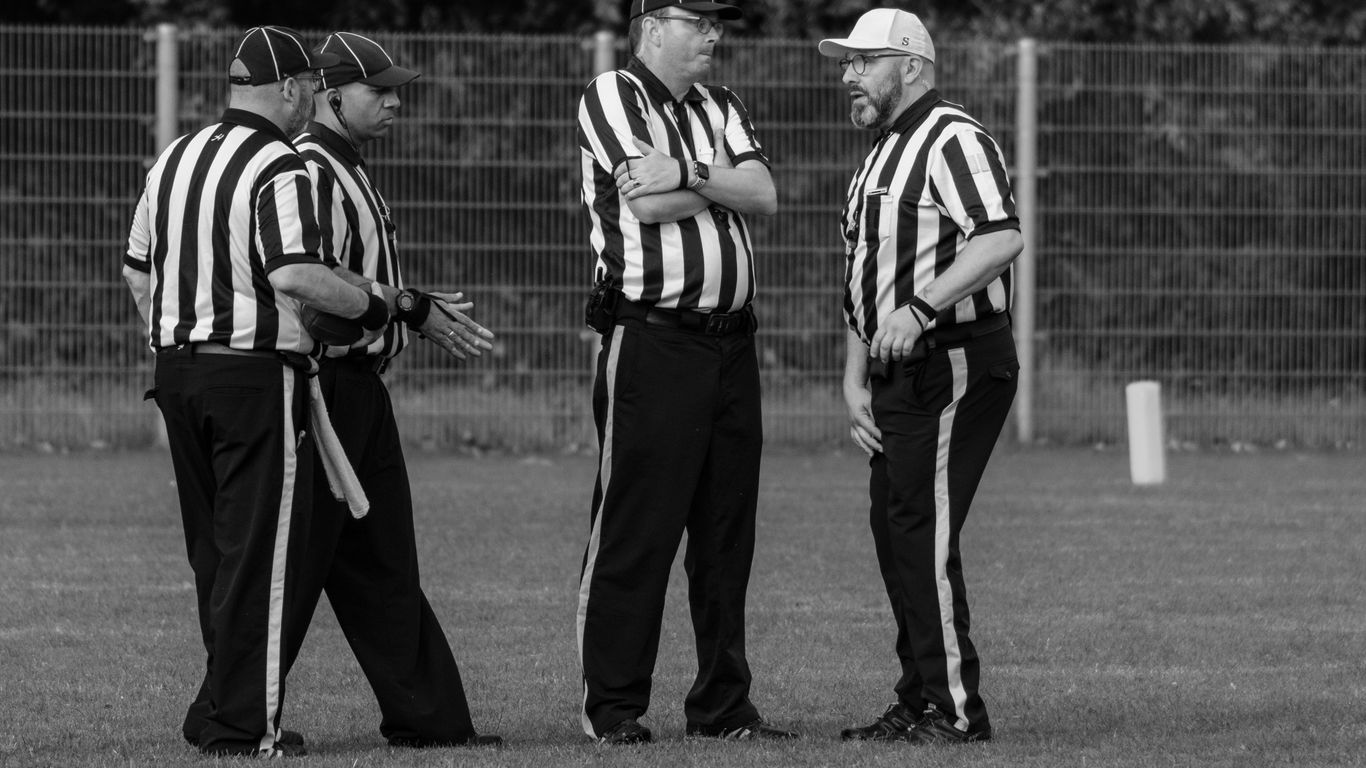 Four referees in striped shirts on a field