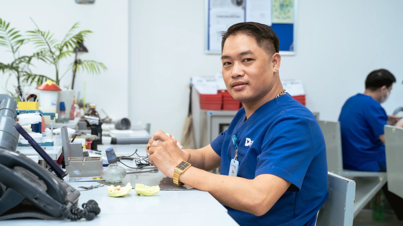 A person works on dental prosthetics in a laboratory setting.