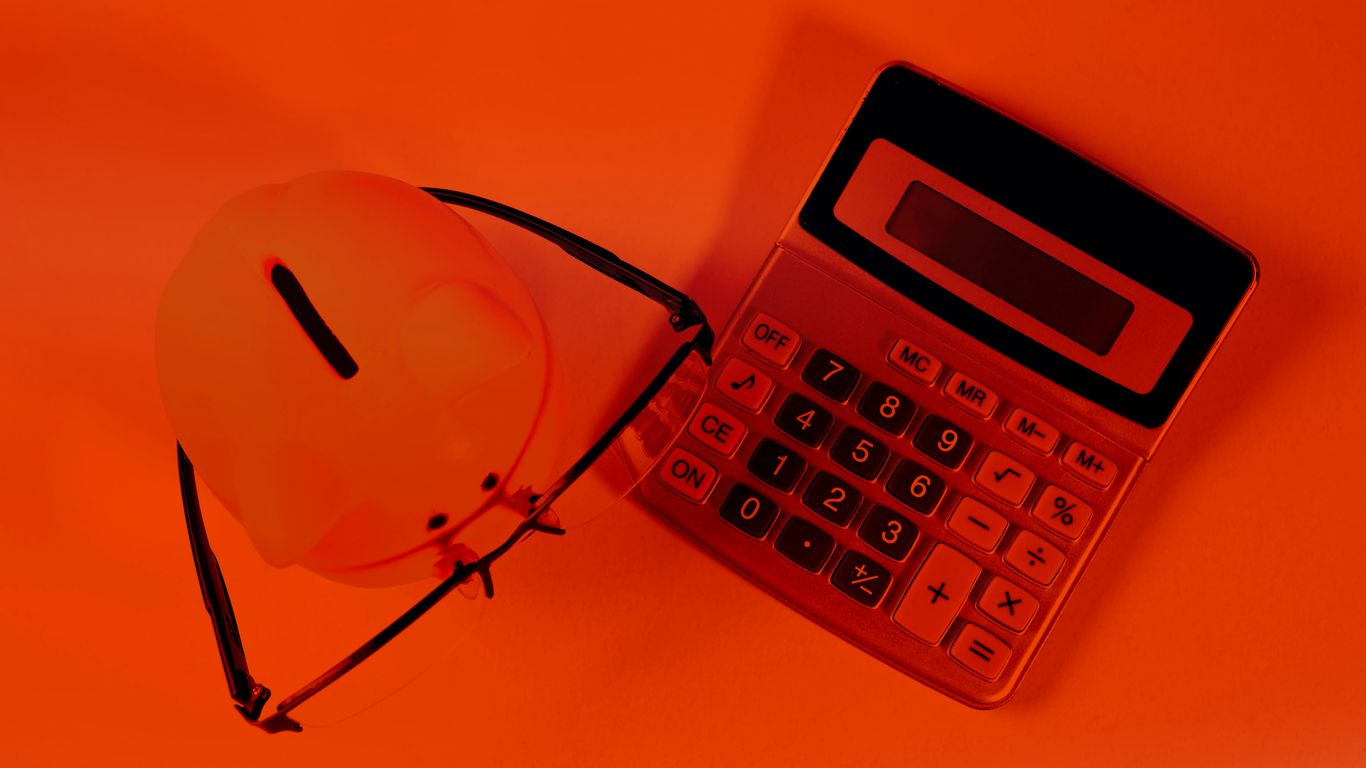 A piggy bank and calculator on an orange background.