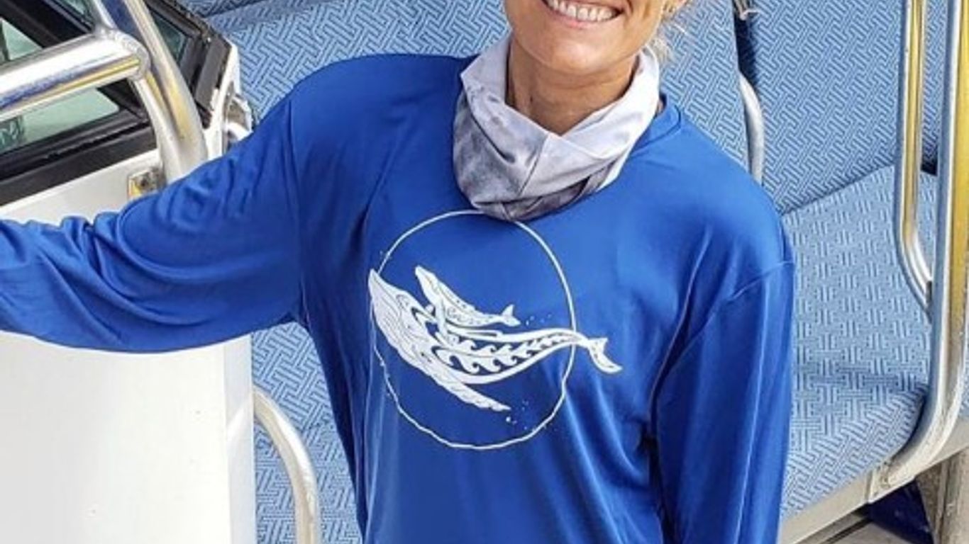 A person in a blue shirt with a whale design on a boat.