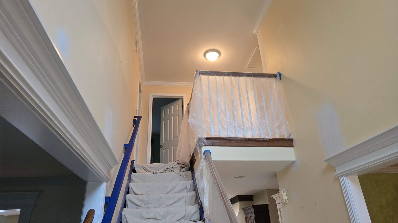 Interior staircase and hallway covered in plastic sheeting for painting.