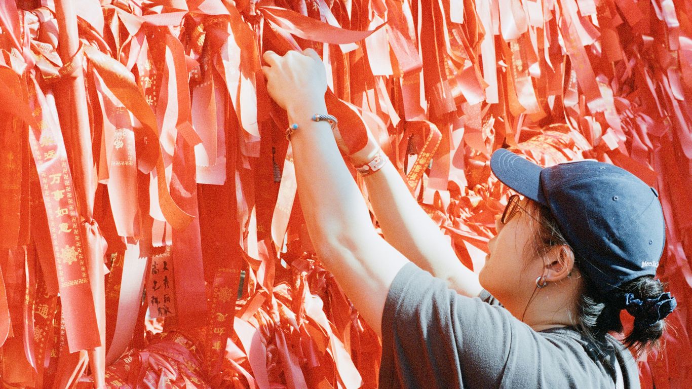 Person attaching red ribbons to a wall
