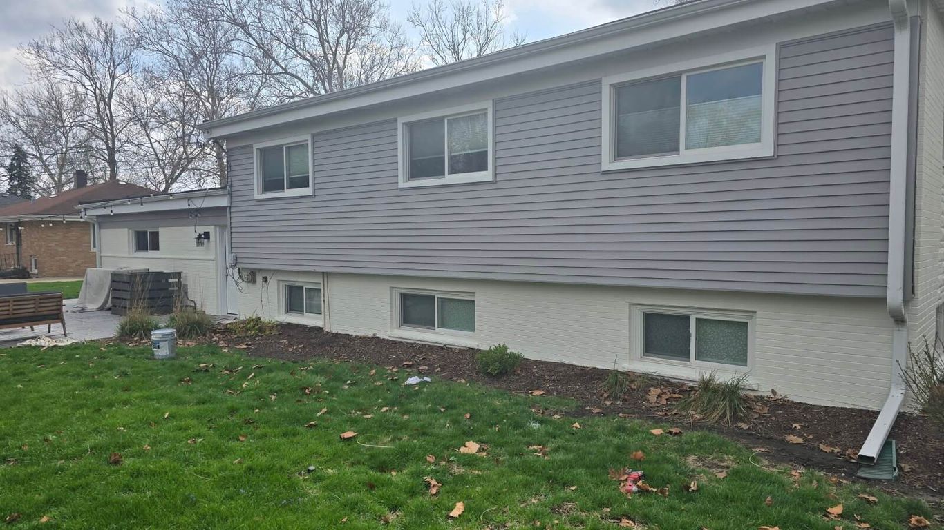 A house with gray siding and white painted brick foundation.