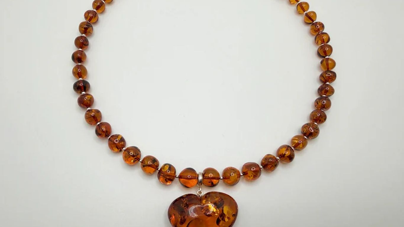 A necklace with amber beads and a heart-shaped pendant.