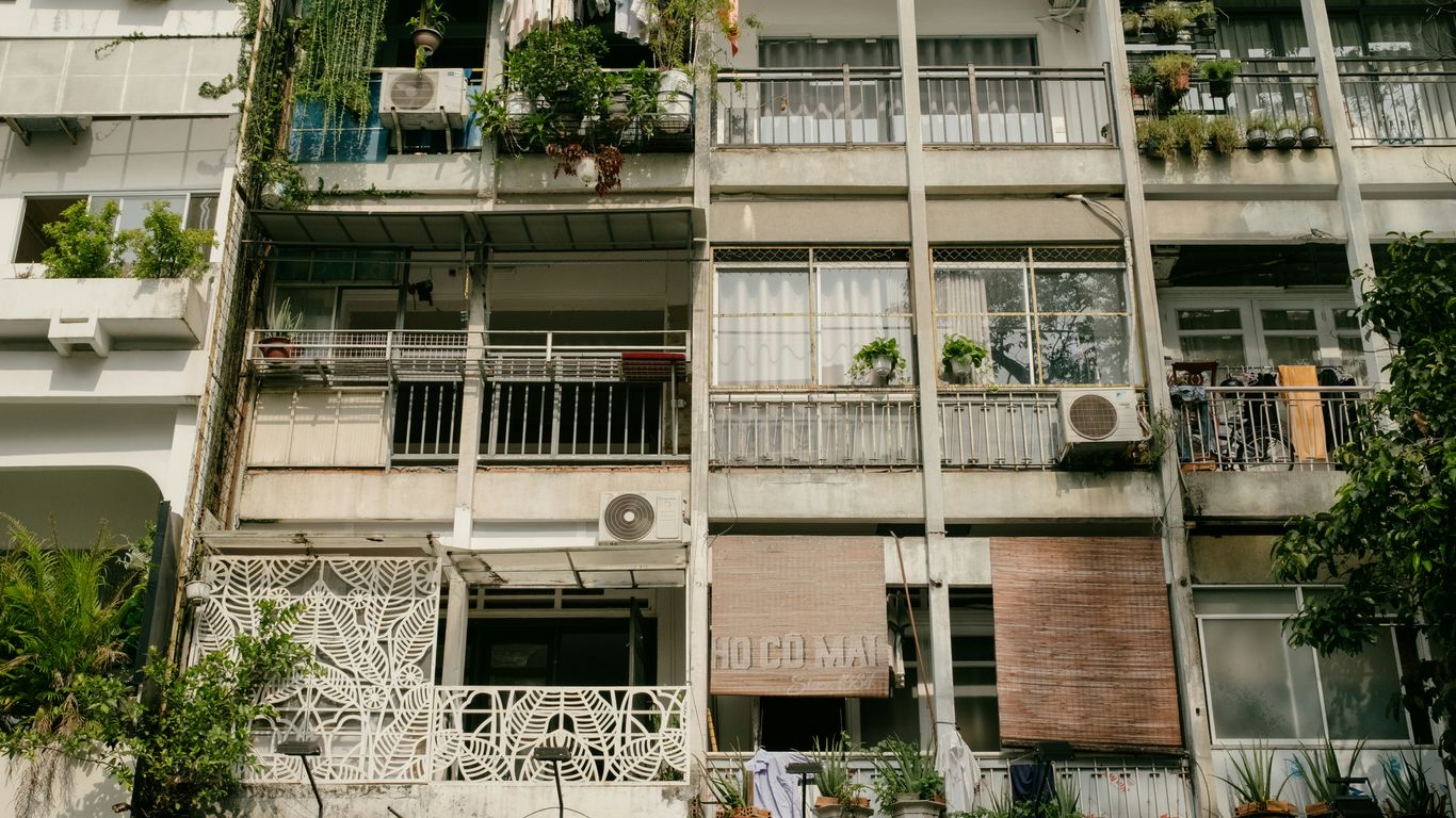 Apartment building balconies with plants and air conditioners.