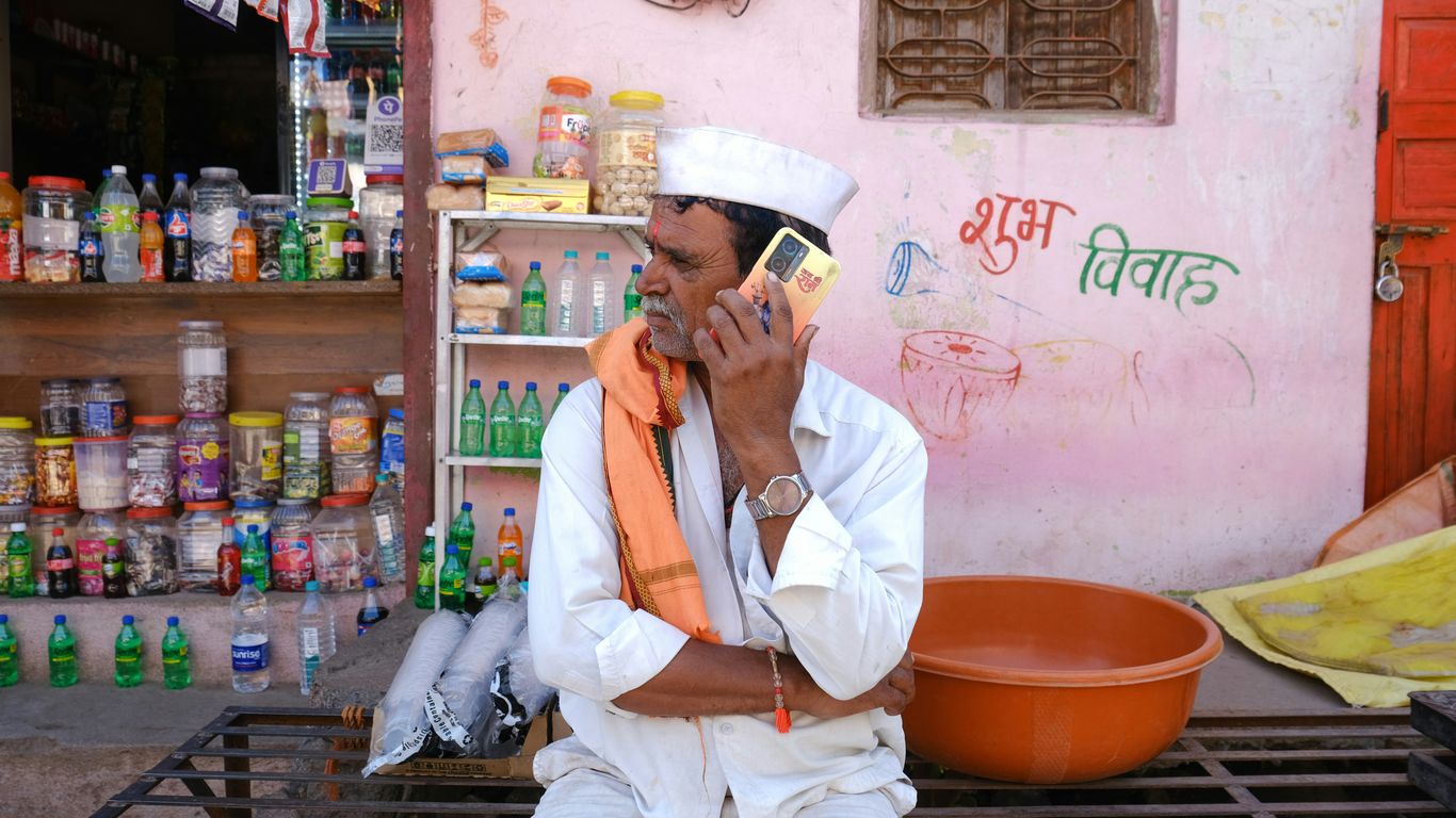Man in traditional indian attire talking on phone.
