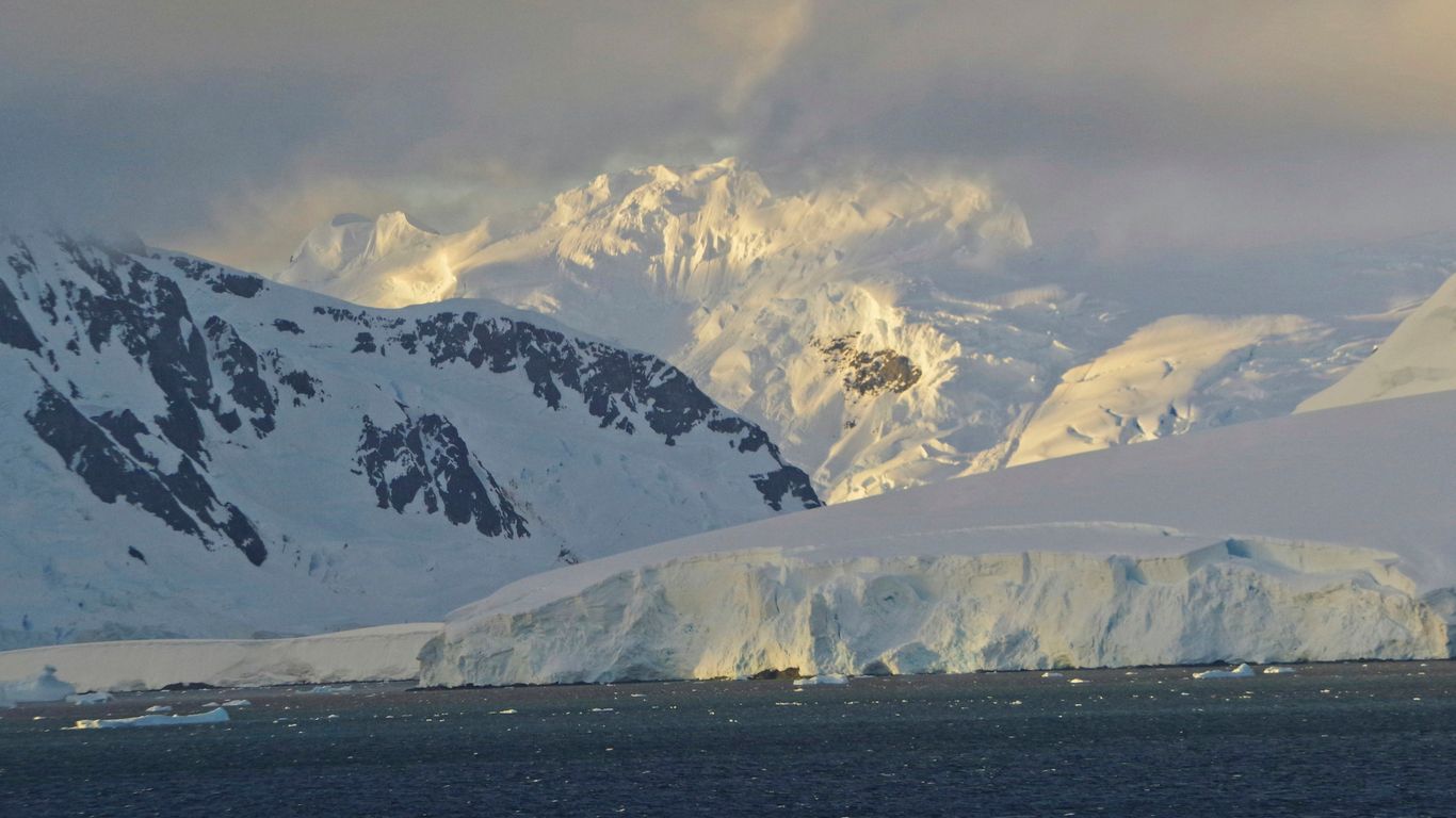 Snow-covered mountains and icebergs in the ocean.