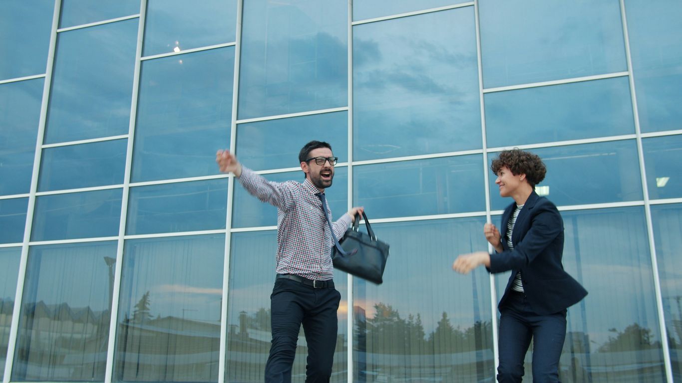 Two business people celebrating outside modern office building