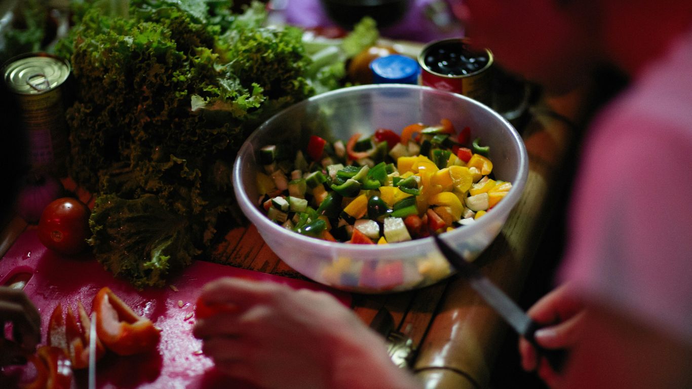 a person cutting up vegetables on a cutting board