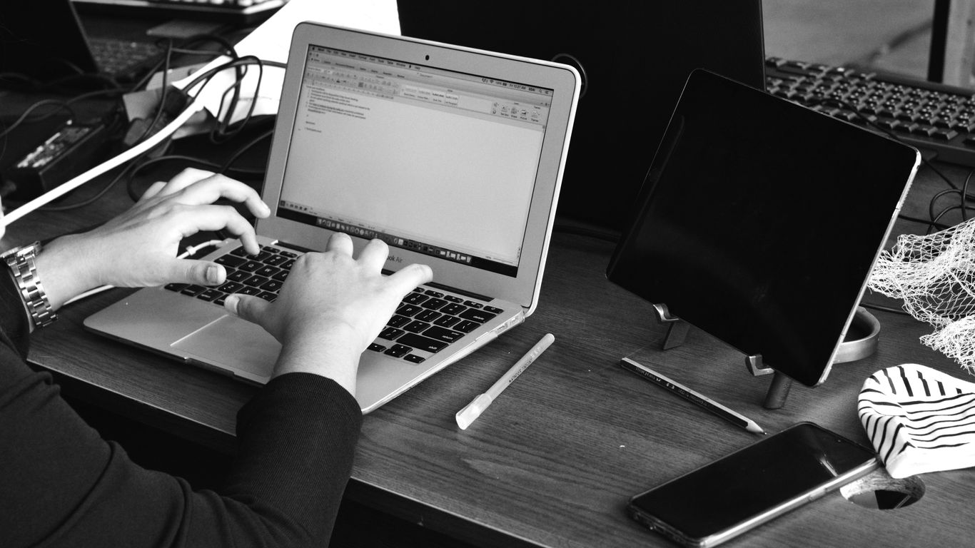 a person sitting at a desk using a laptop computer