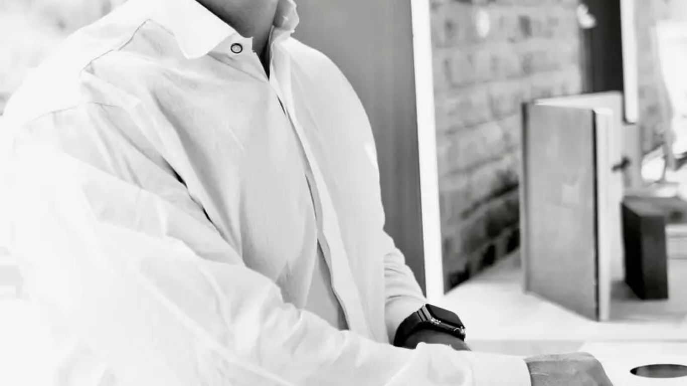 Person smiling while using DJ equipment, indoors, black and white.