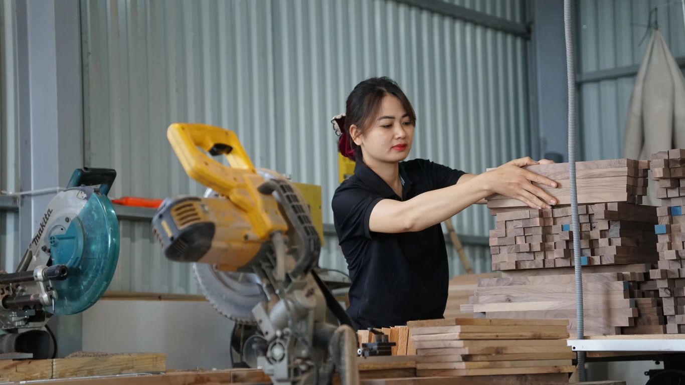 A person works in a workshop with lumber and tools.