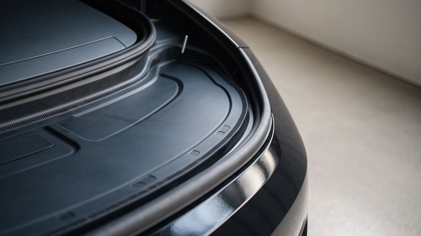 Flexible dark frunk mat beside an open electric sedan