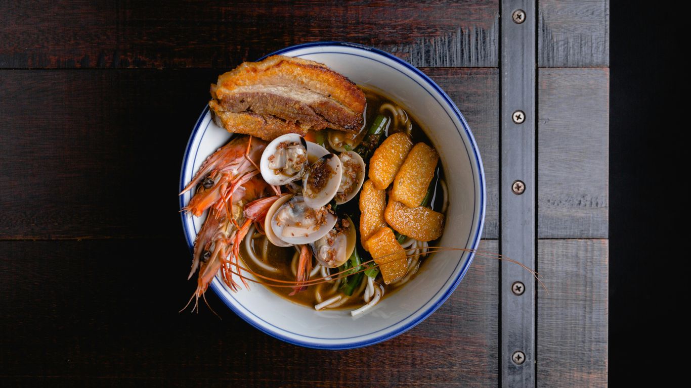 a bowl of soup with shrimp, mussels and bread