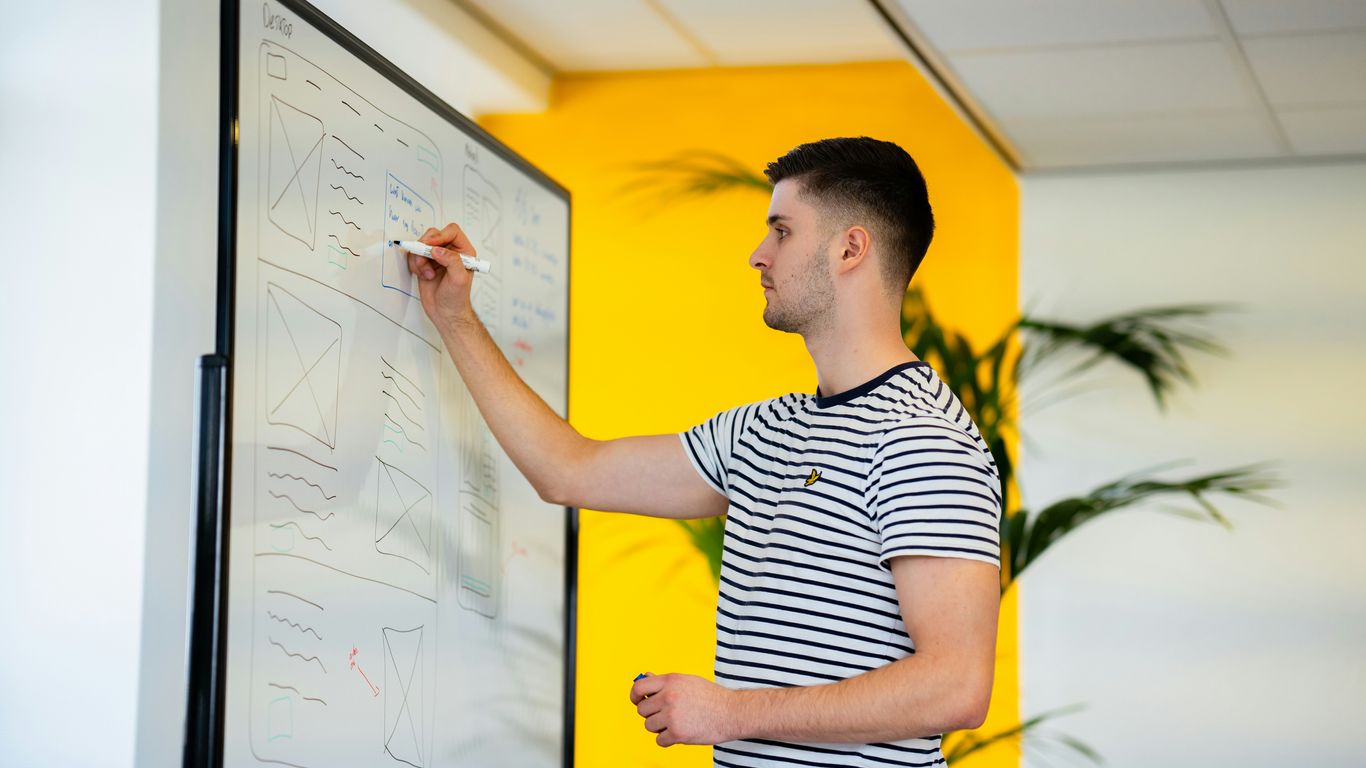 a man standing in front of a whiteboard writing on it