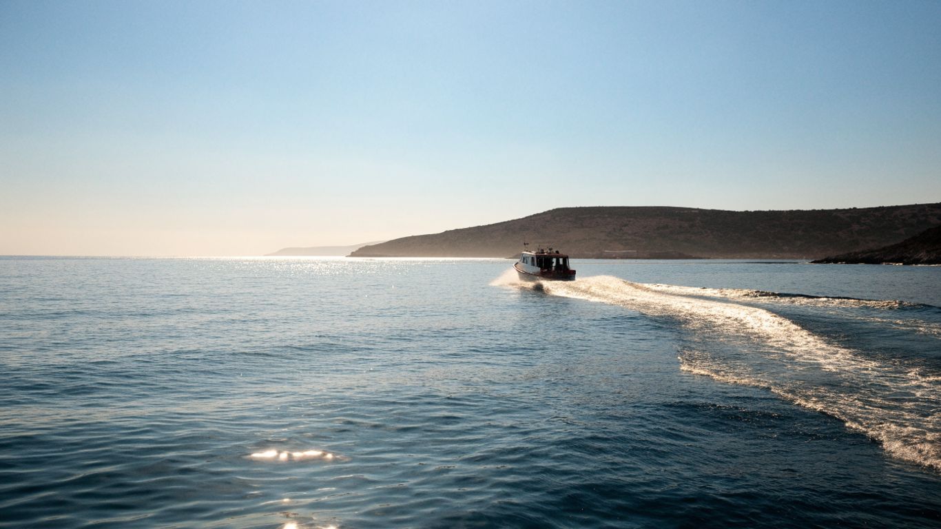 Boat crossing blue water toward a volcanic island