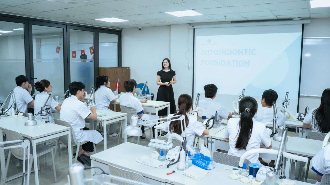 Students in a dental lab class with a presentation on orthodontic foundation.