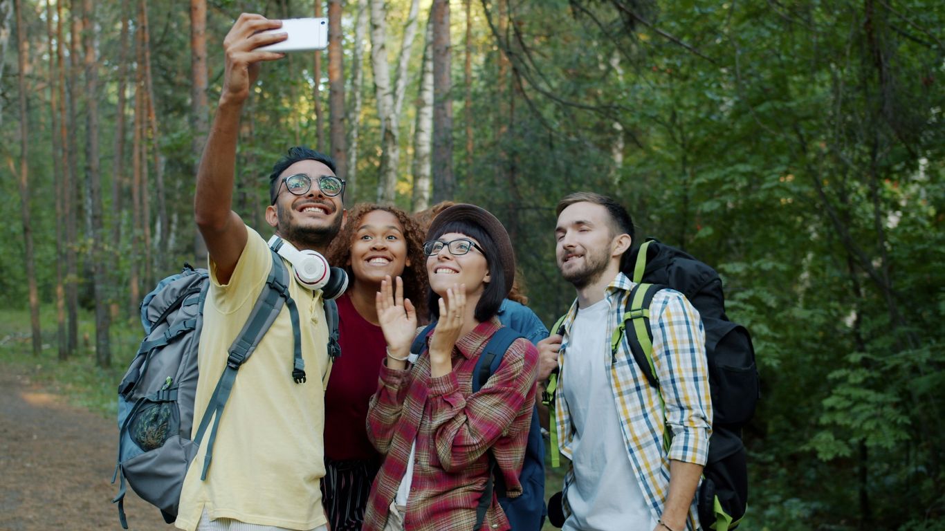 Four friends take a selfie while hiking in the forest.
