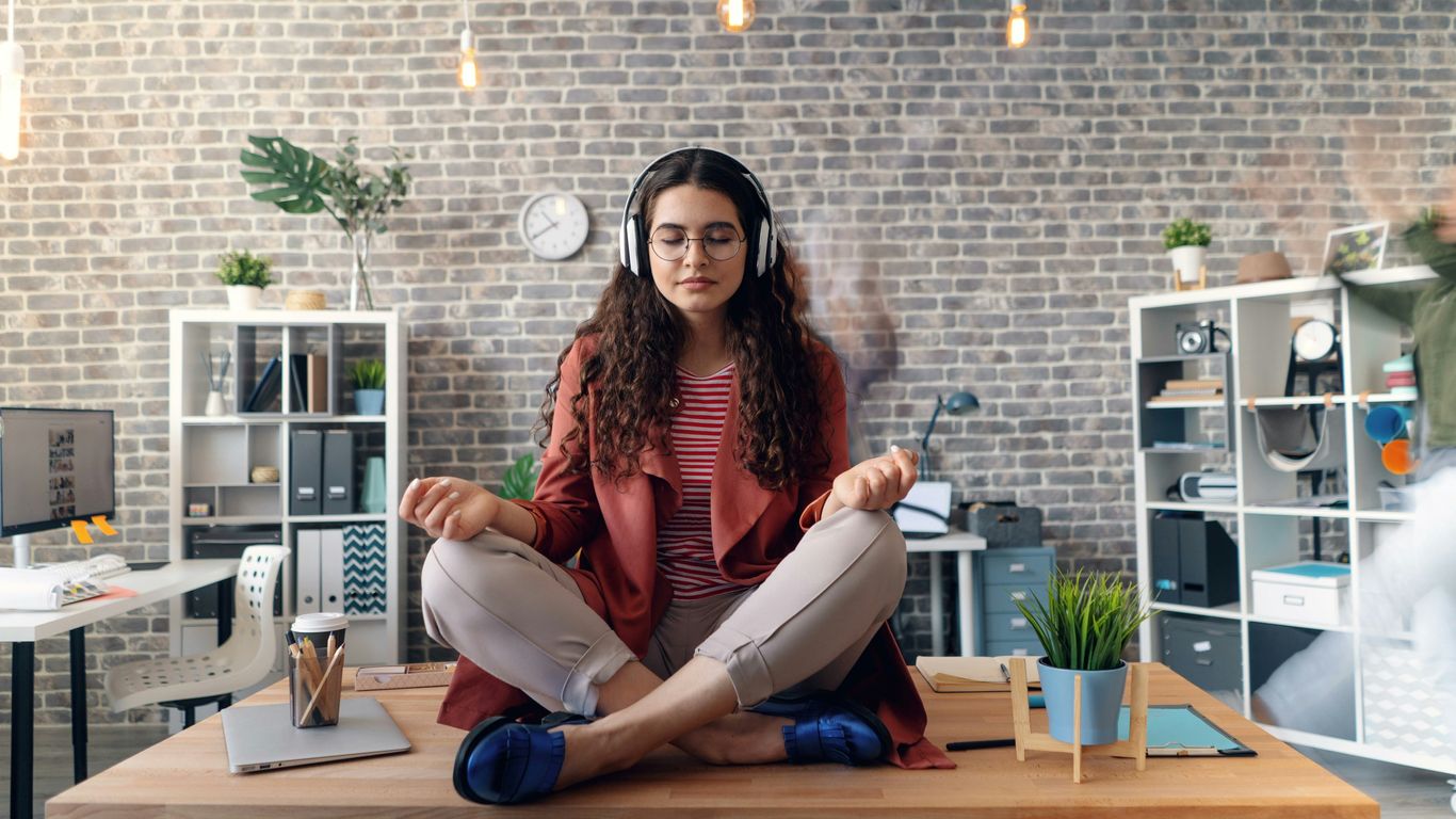 a woman sitting on a desk with headphones on