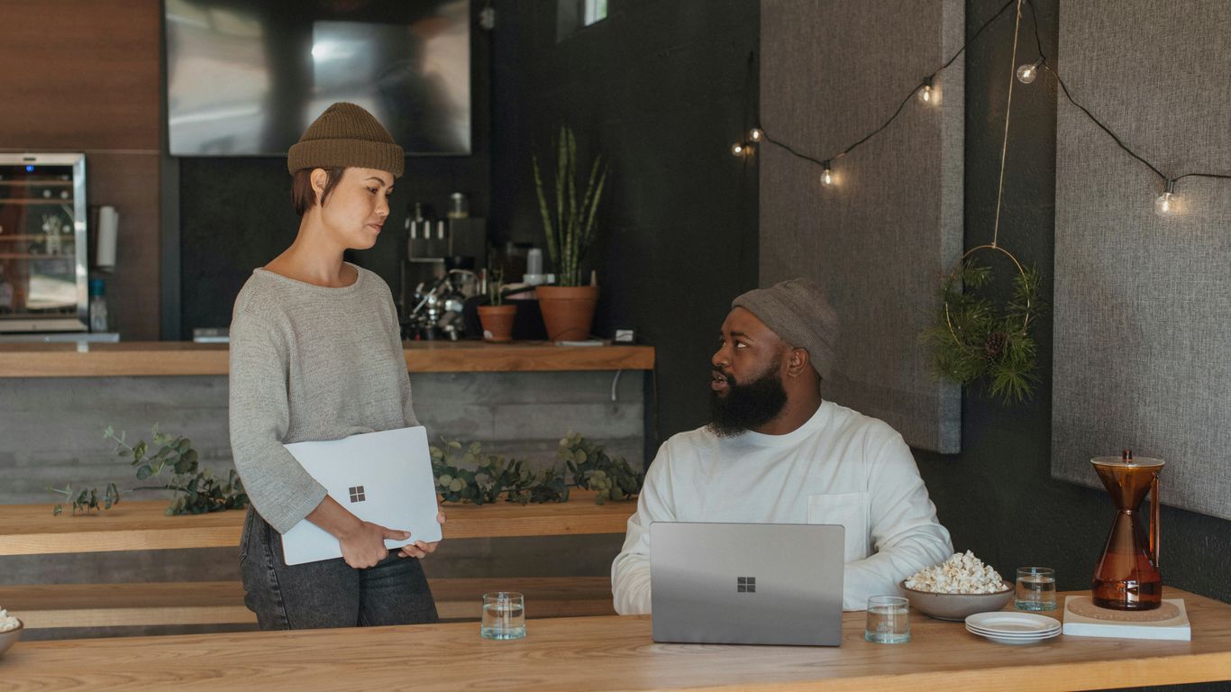 Two coworkers talking at work holding Surface laptops
