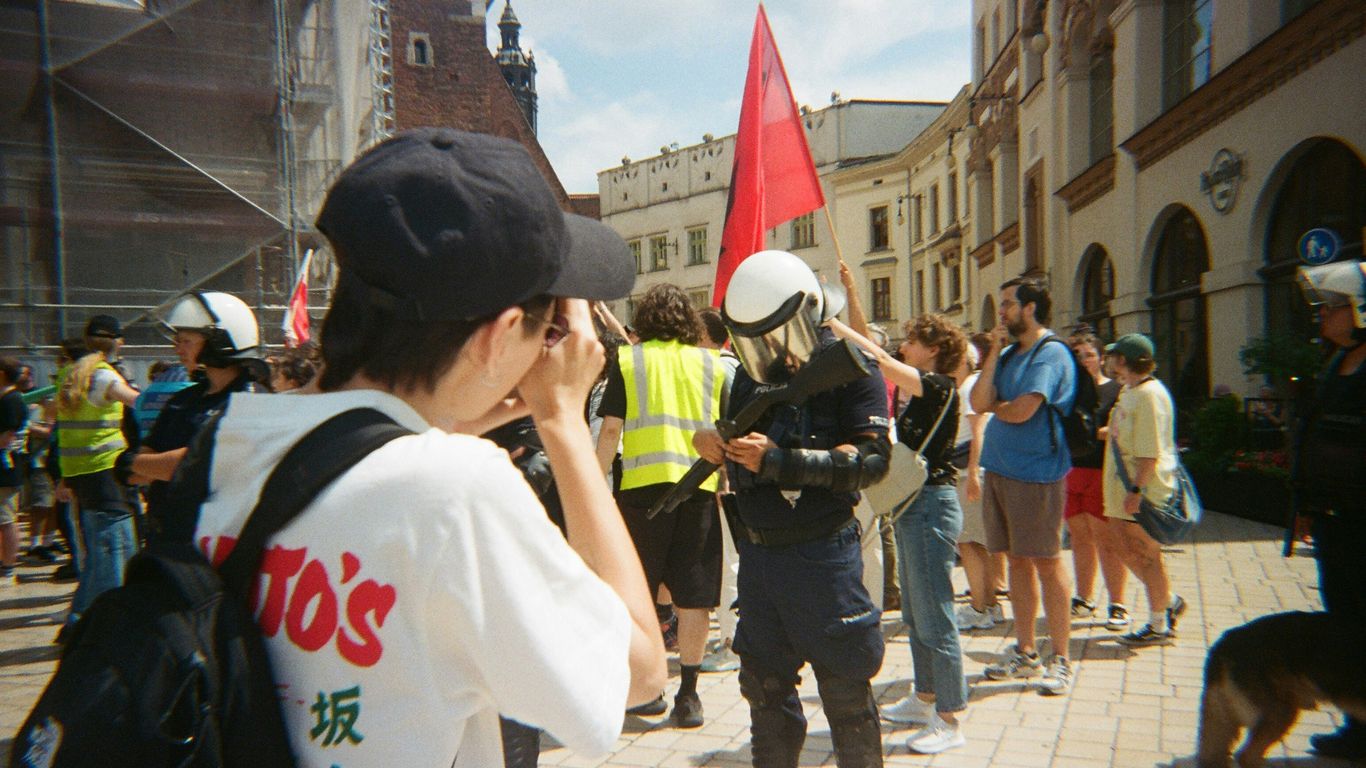 People gathered in a city square with a red flag.