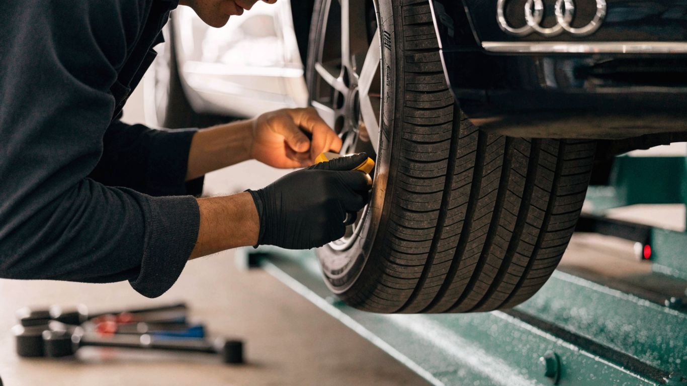 Mechanic checking tire and brake condition on Audi