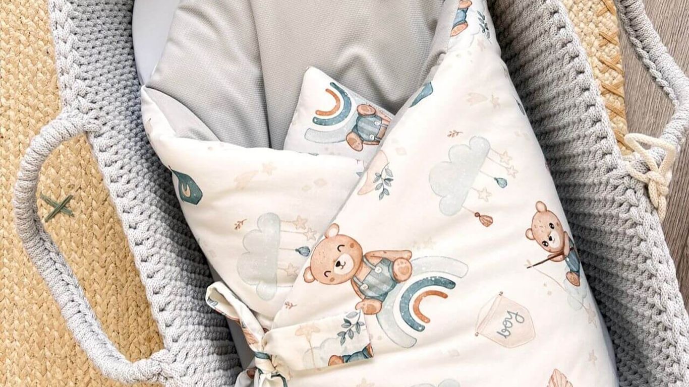 A baby bassinet with a teddy bear themed swaddle and bedding.