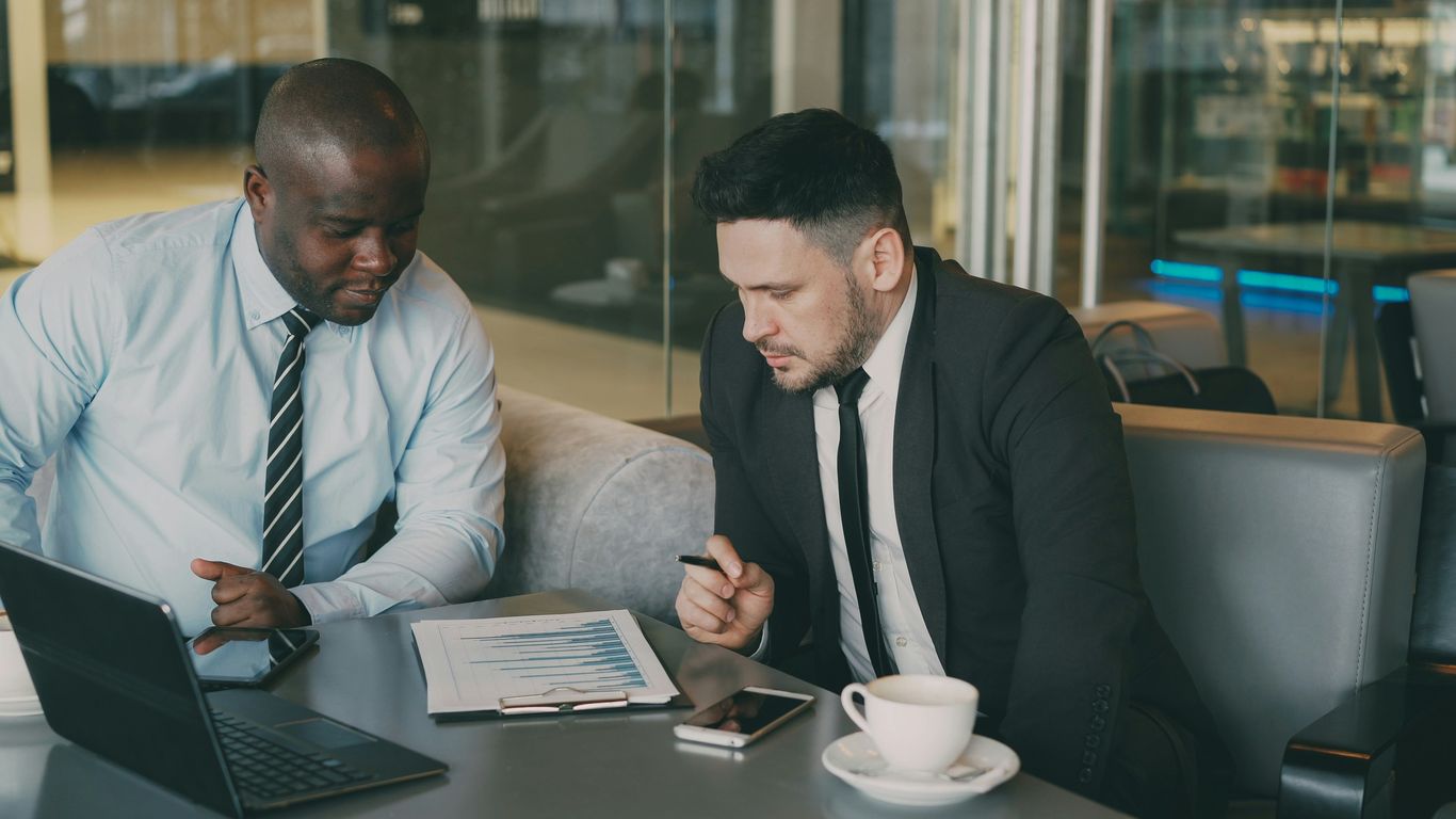 Two businessmen reviewing documents at a table.