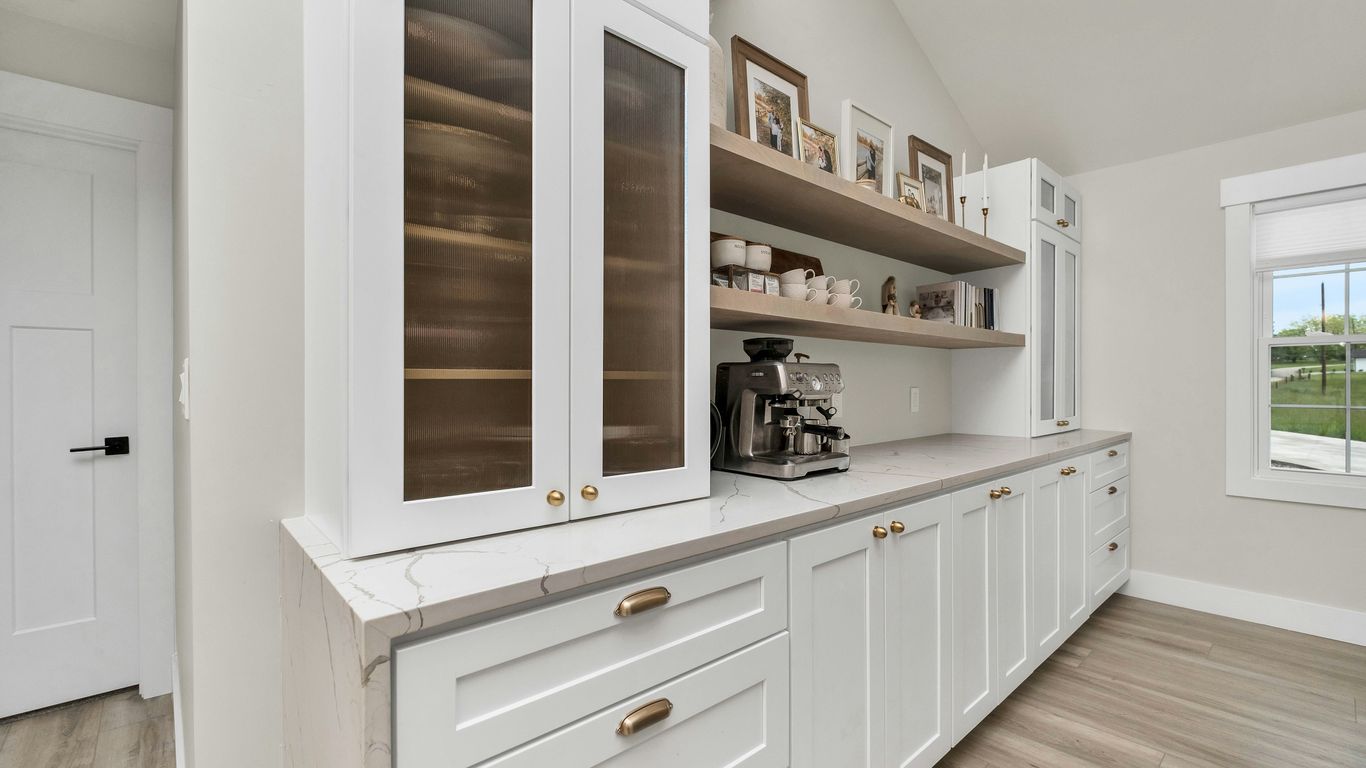 a kitchen with white cabinets and wood floors