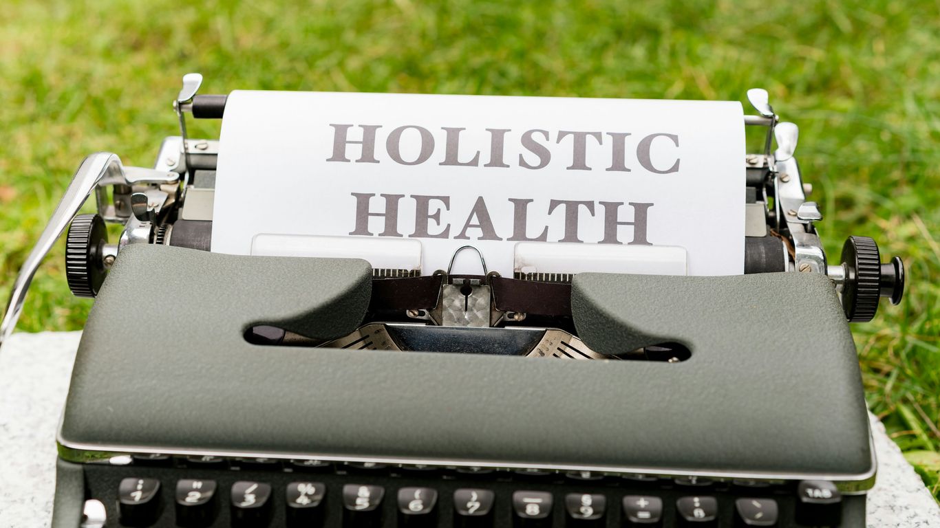 a close up of a typewriter with a paper that says holstic health
