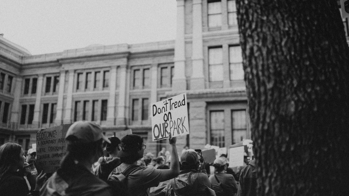 People protest in front of a building holding signs.