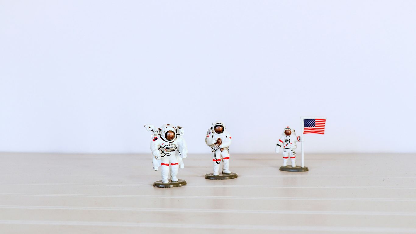 three astronaut figures on gray surface