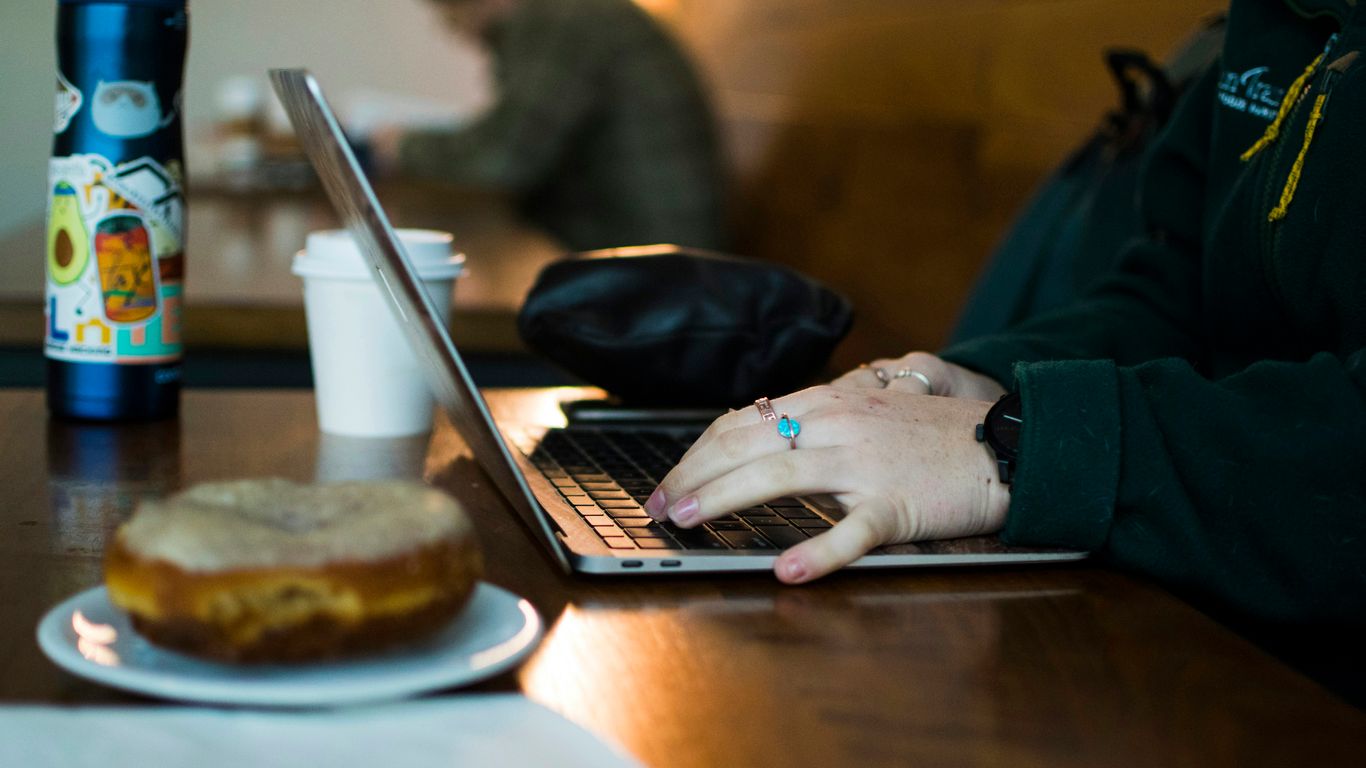 a person using a laptop on a wooden table